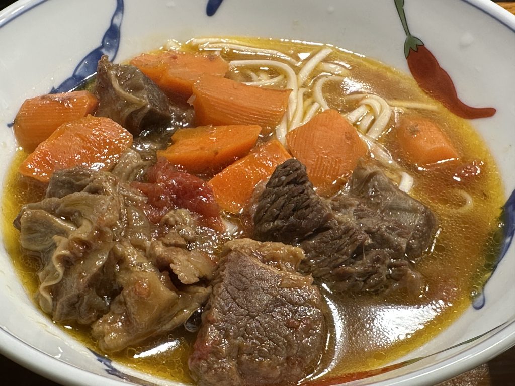 Braised beef brisket with carrots and tomatoes served with noodles